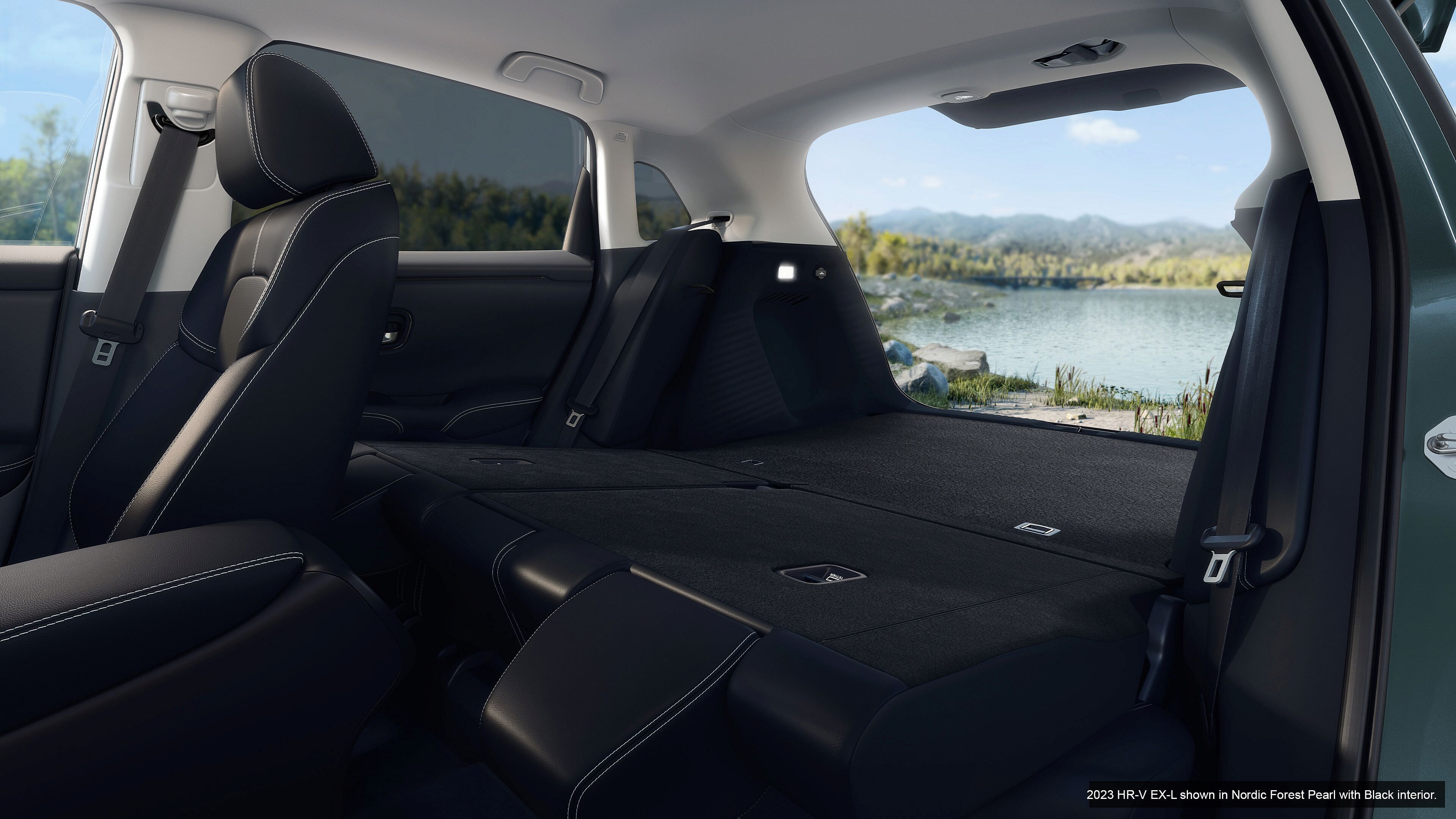 Folded rear seats in Nordic Forest Pearl Honda HR-V EX-L 2023, open trunk. Lake in background